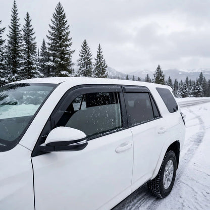 White Toyota 4Runner with smoke window visor rain guards installed in snowy weather