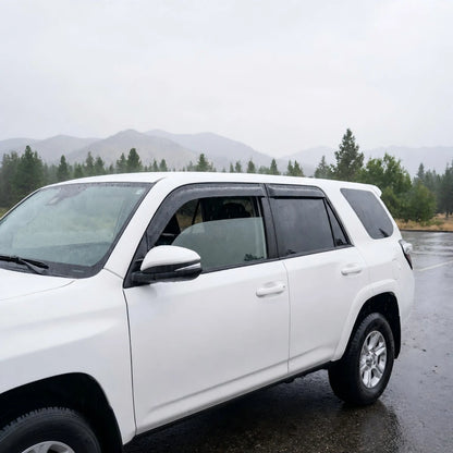 White Toyota 4Runner with smoke tape-on window vent deflectors installed in rainy weather