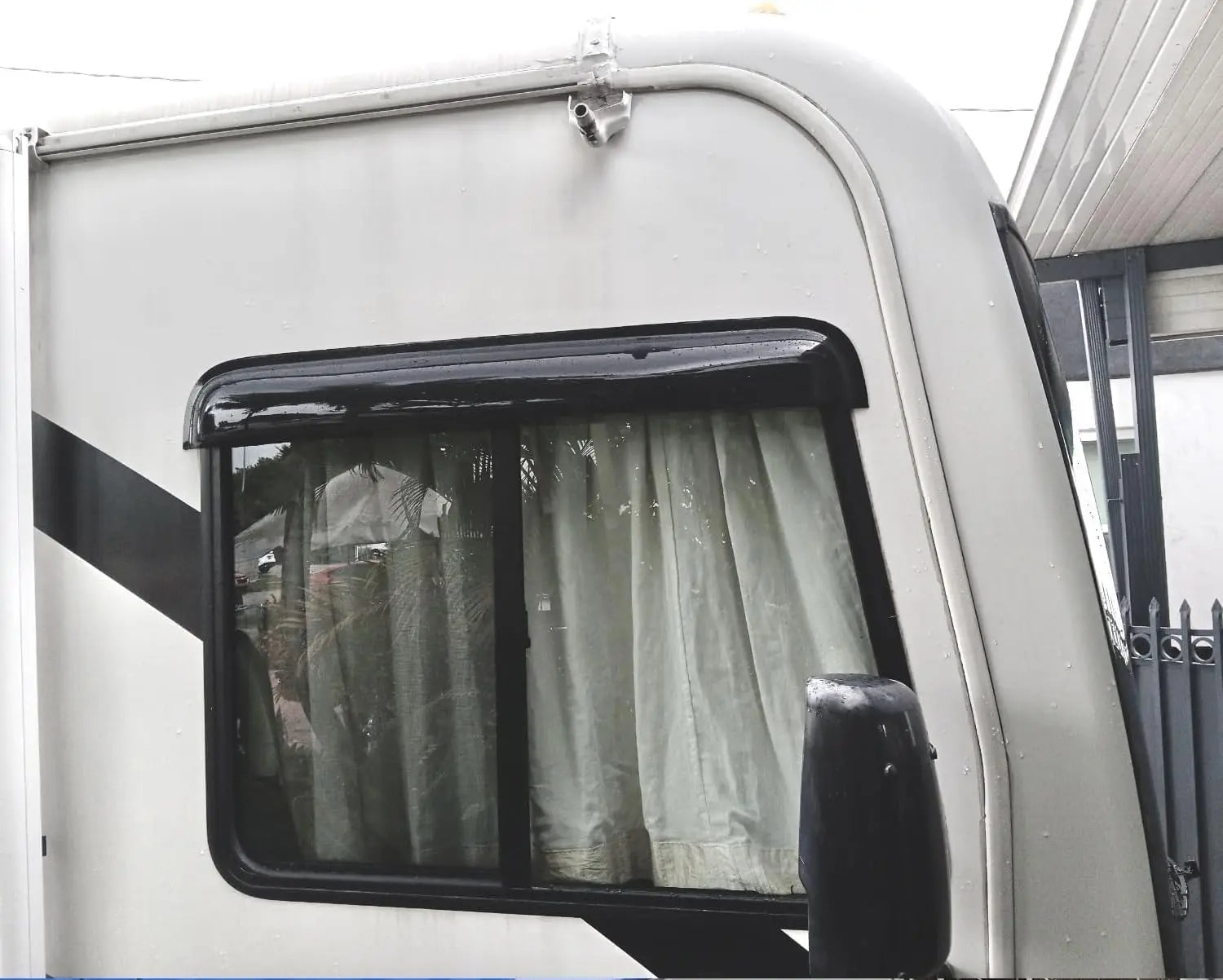 Universal dark smoke visor wind deflector installed above an RV side window for rain protection and ventilation